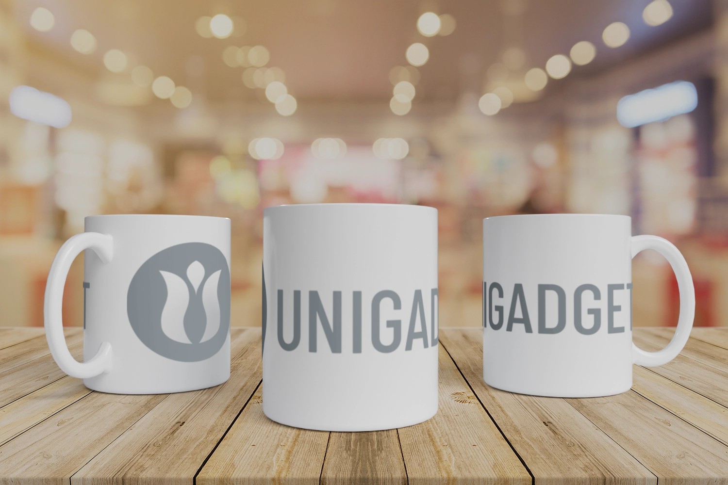 Tre tazze per sublimazione bianche con stampa di logo aziendale, esposte su un tavolo di legno.